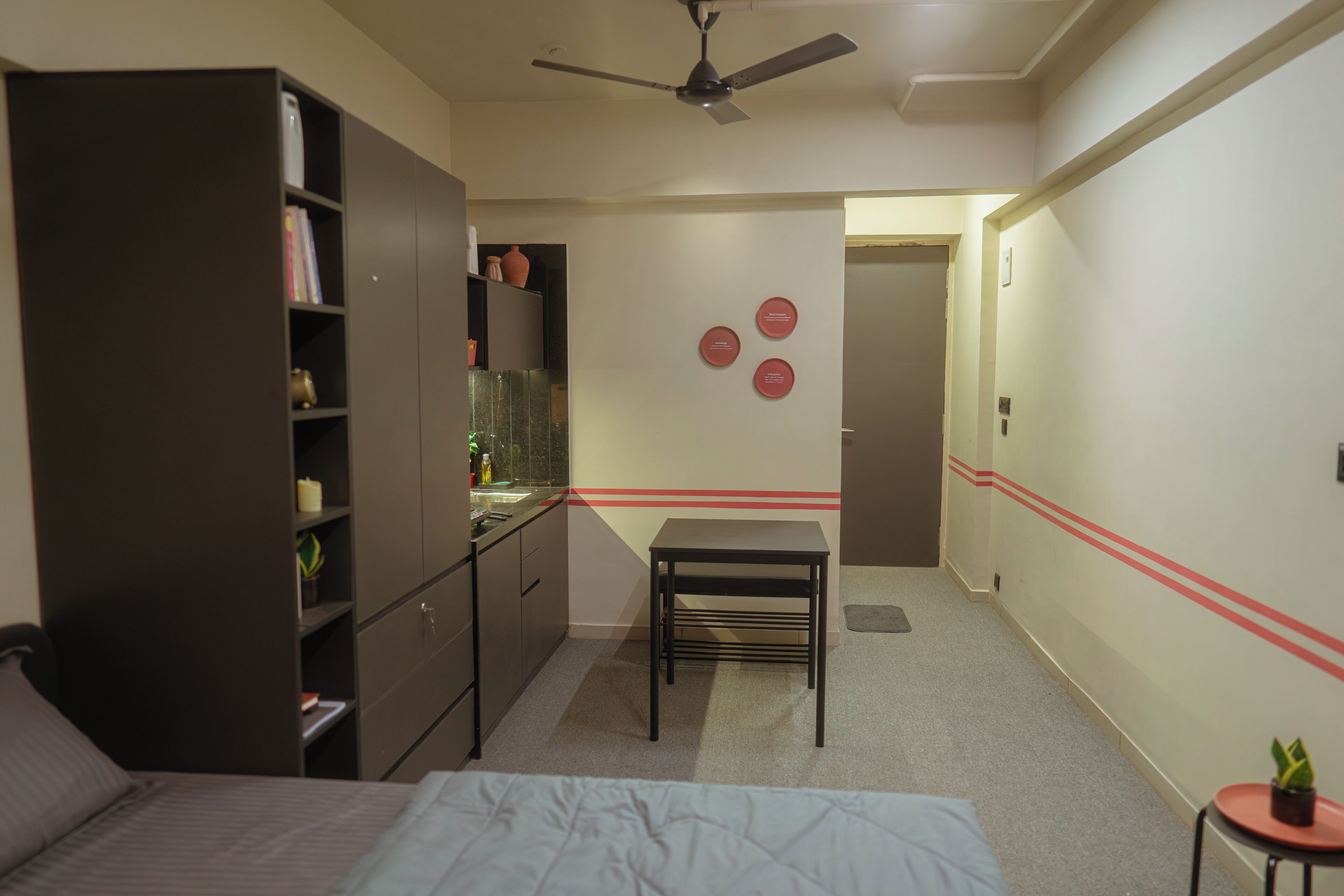 Une chambre à coucher comprenant un lit, une armoire, un bureau et un ventilateur de plafond.