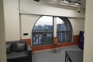 A room with a large arched window, a sofa, a small table, and a hanging plant.