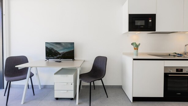 Une cuisine moderne équipée d’un four à micro-ondes, d’un four traditionnel et d’un petit coin repas avec un bureau et des chaises.