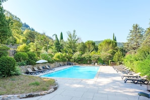 A swimming pool with lounge chairs and a stone wall.