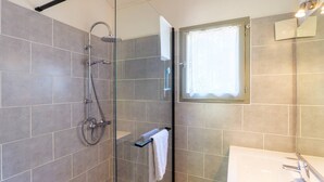 A modern bathroom with a glass-enclosed shower, a towel rack, and a window with a curtain. - “Comfort Shared Pool” Chalet with Pool, Shared Terrace, and Wi-Fi (Les Vans)