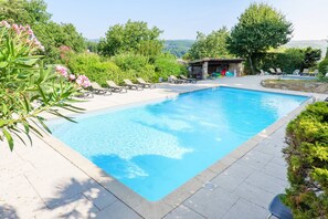 A rectangular swimming pool with clear blue water, surrounded by lounge chairs and greenery. - Chalet 'Confort Piscine Partagée' with pool, shared terrace and Wi-Fi (Les Vans)