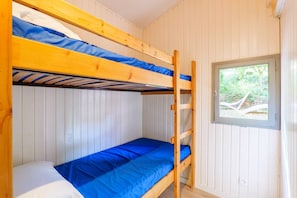 A bunk bed room with white walls and a window.