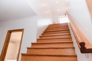 Una escalera de madera con barandilla que lleva a una puerta en la parte superior.