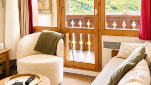 A cozy living room with a sofa, a chair, a small table with a tray, and a view of a mountainous landscape through large windows. - Thémis 112 - The Alpine Cocoon (La Plagne Tarentaise)