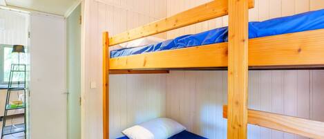 Una cama litera con colchón azul y almohada blanca en una habitación con paneles blancos.