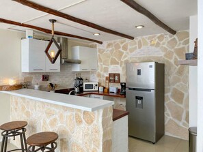 Eine Küche mit Steinwand, einem Edelstahl-Kühlschrank, einer Mikrowelle und einer Bar mit Hockern.