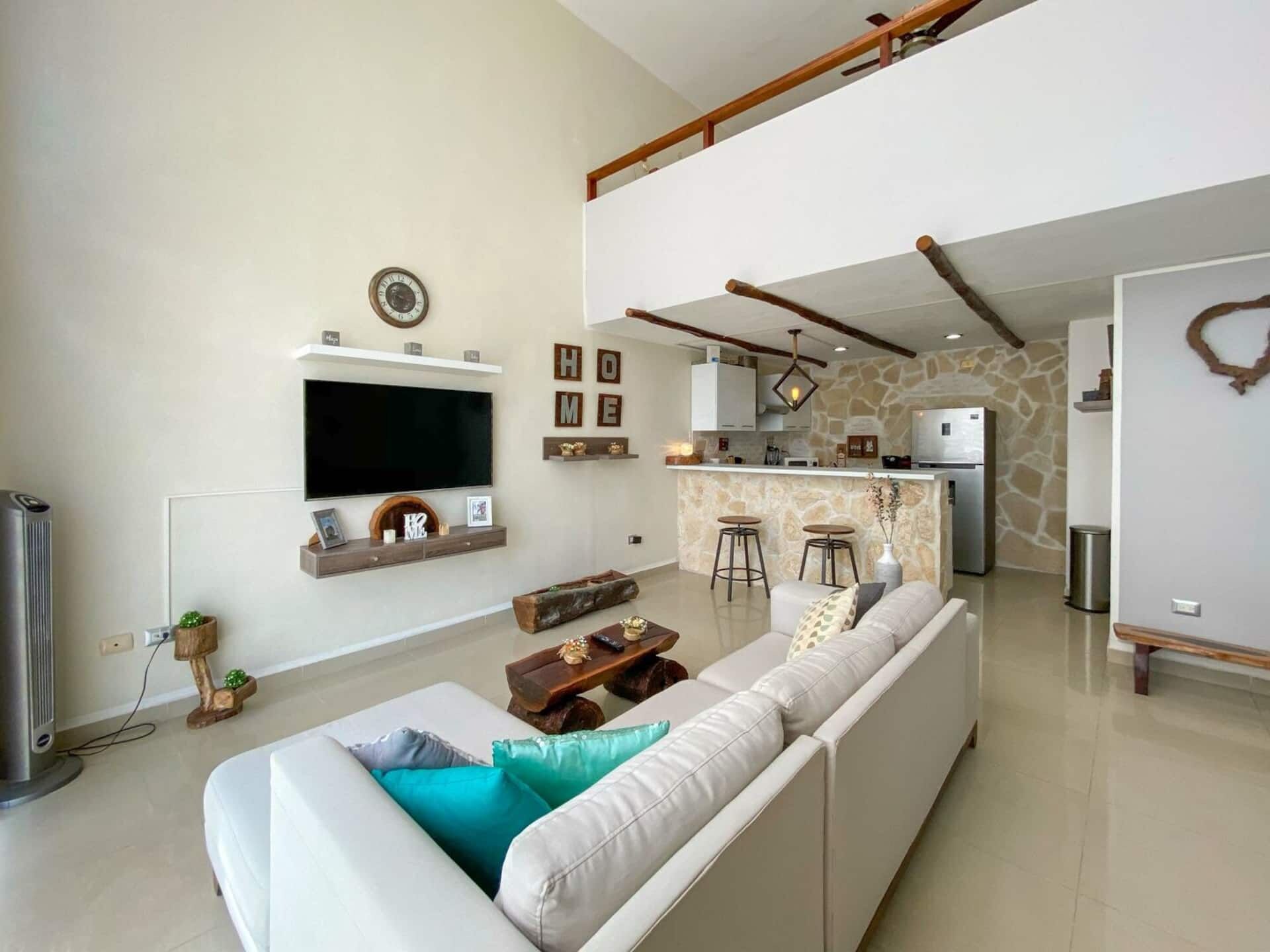A modern living room with a sofa, a flat-screen TV, and a stone wall.