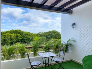 Eine Außenpatio mit Tisch und Stühlen, einer an der Wand befestigten Leuchte und Blick auf ein bewaldetes Gebiet.