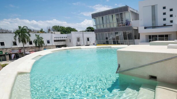 Piscina límpida com um edifício moderno ao fundo.