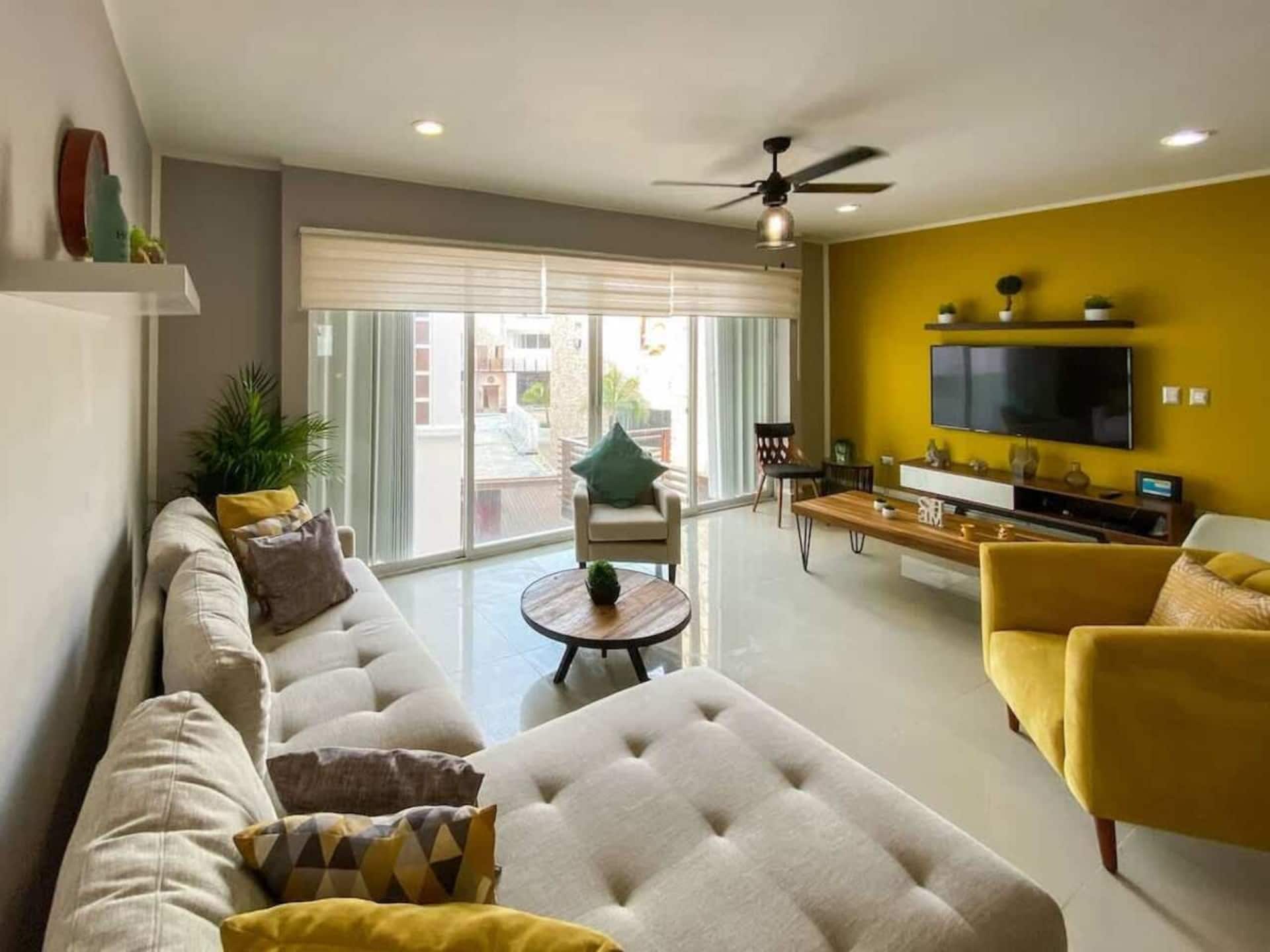 Un salon moderne avec un canapé, des fauteuils, une table basse et un téléviseur.