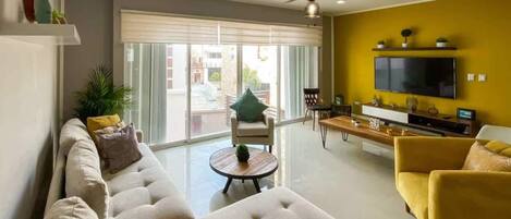 Un salon moderne avec un canapé, des fauteuils, une table basse et un téléviseur.