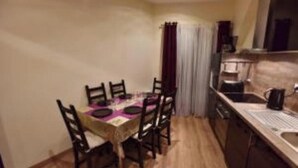 A compact kitchen with a dining table and chairs, a coffee machine, and a sink. - Deluxe Loft at Le Moulin Vert (Paris)