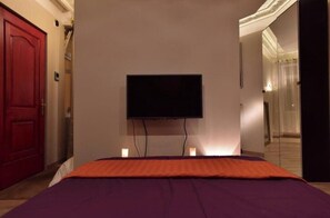 Ein Hotelzimmer mit einem Bett, einem an der Wand montierten Fernseher und einer roten Tür.