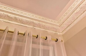Ein Badezimmer mit dekorativer Decke, einer Vorhangstange und einem Vorhang.