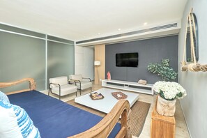 Ein modernes Wohnzimmer mit einer Couch, Sesseln, einem Couchtisch, einem Fernseher und einer Pflanze.