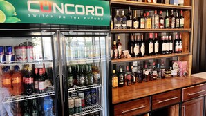 A bar area with a refrigerated display case and shelves stocked with various alcoholic beverages.