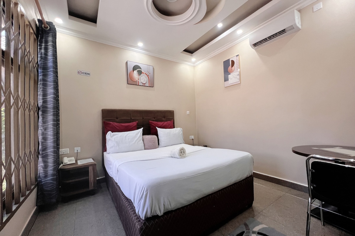Una habitación de hotel con cama, mesita de noche, silla y obras de arte en las paredes.