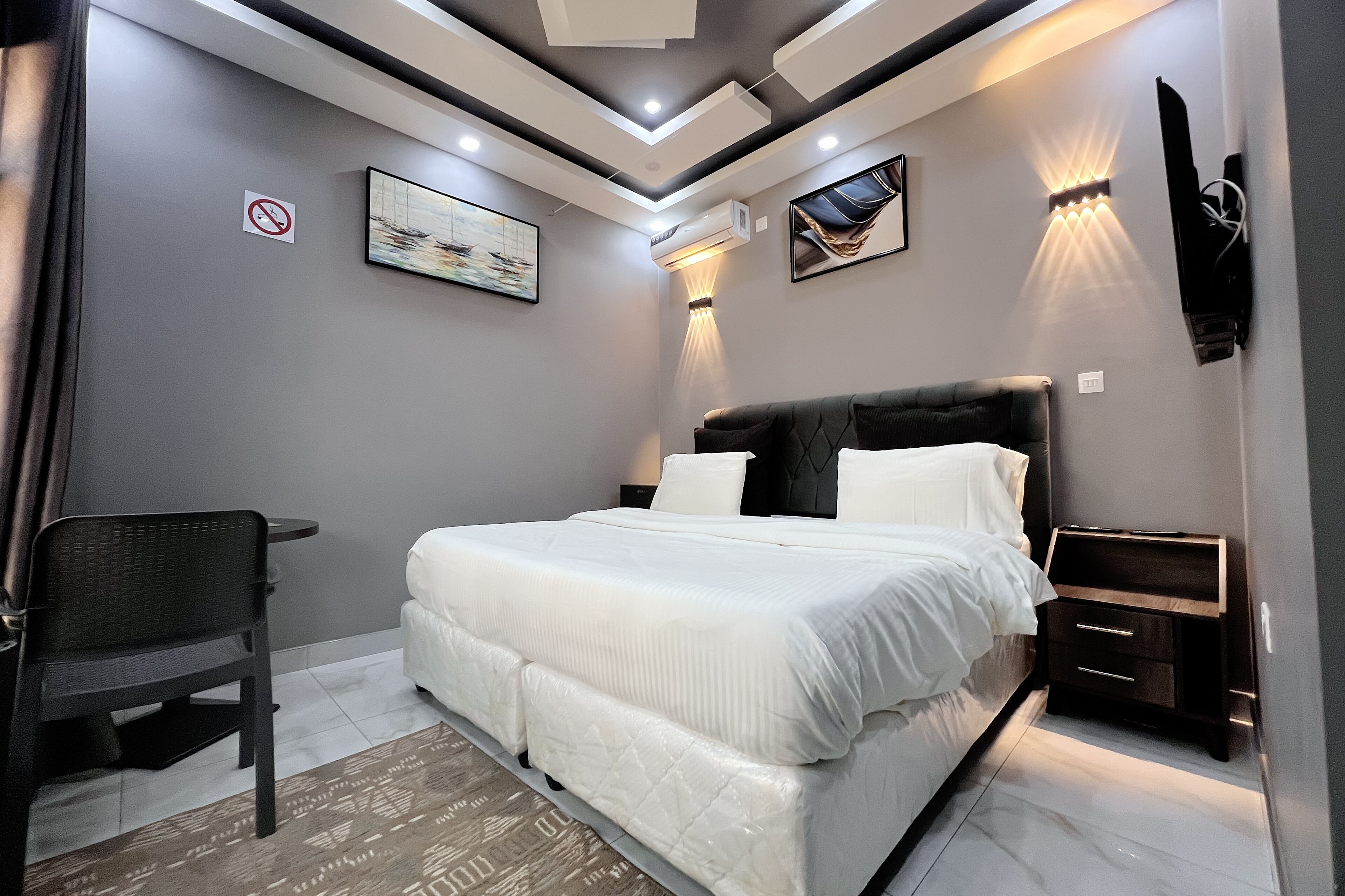 Un dormitorio moderno con cama, mesitas de noche, escritorio y obras de arte en las paredes.
