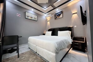 A modern bedroom with a bed, bedside tables, a desk, and artwork on the walls.