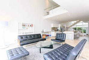 Ein modernes Wohnzimmer mit einer Couch, einem Hocker und einem Glastisch.