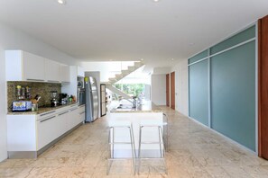 A modern kitchen with a central island, stainless steel appliances, and a view to a balcony. - Magia resort condo w/ pool & balcony (Playa del Carmen)