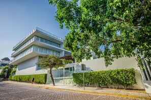 A modern building with a flat roof, large windows, and a balcony. - Magia resort condo w/ pool & balcony (Playa del Carmen)