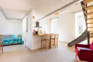 Une cuisine avec un coin repas, un escalier et un canapé agrémenté de coussins colorés.