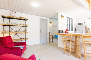 Une cuisine moderne avec des étagères en bois, une table à manger et une chaise rouge.