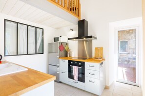 Eine moderne Küche mit Holztischplatte, Edelstahlgeräten und einem großen Fenster.