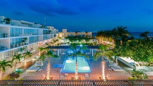 A resort with a swimming pool, lounge chairs, and a view of the ocean. - Beachside escape w/ pool & balcony (Playa del Carmen)