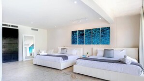 A modern hotel room with two beds, a large window, and a wall with a blue abstract painting. - Beachside escape w/ pool & balcony (Playa del Carmen)