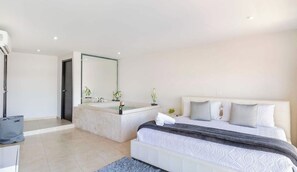 A modern bedroom with a large bed, a built-in bathtub, and a separate shower area. - Beachside escape w/ pool & balcony (Playa del Carmen)