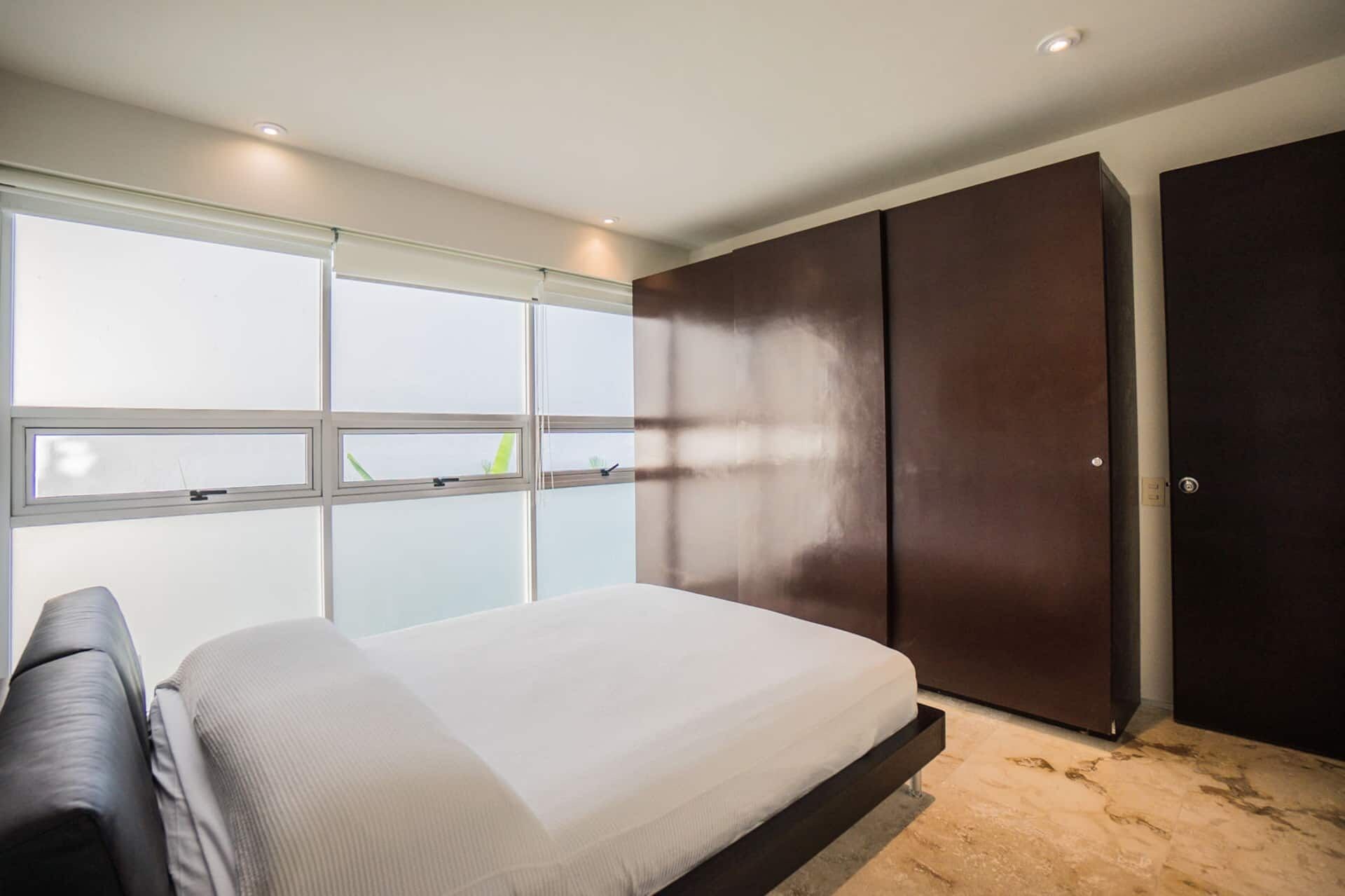A bedroom with a bed, a wardrobe, and a window.