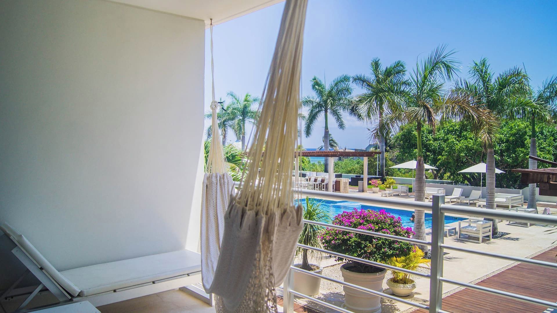 Ein Balkon mit Blick auf einen Poolbereich, einschließlich Liegestühlen und einer Palme.