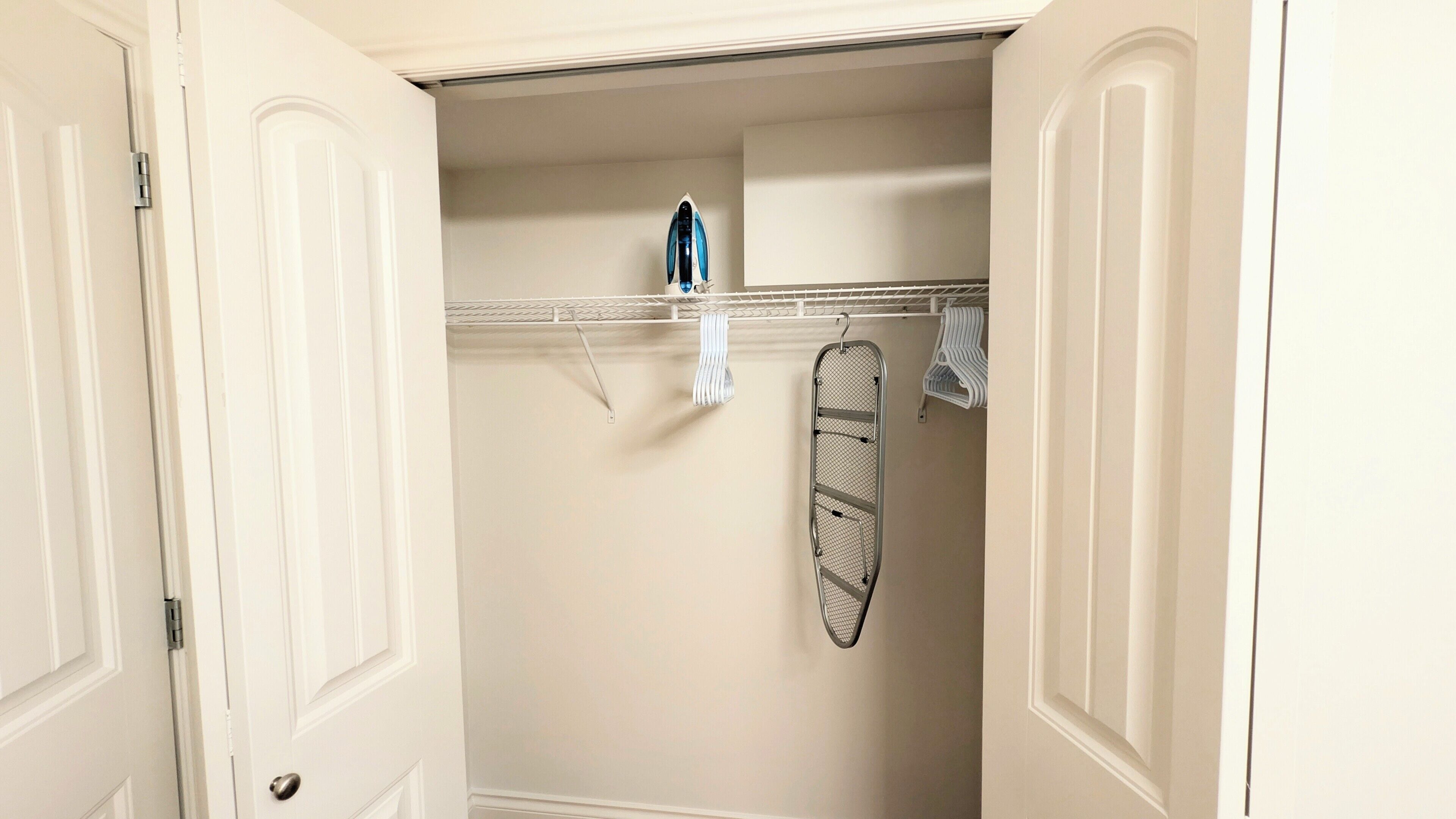 A walk-in closet with a hanging rack, a shelf, and a door.