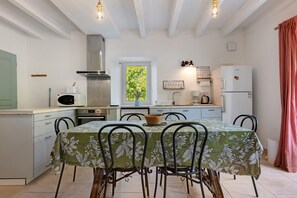 Een kleine keuken met een eettafel, stoelen en basisapparatuur.