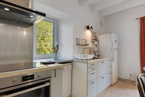 Una cucina moderna con forno integrato, cappa in acciaio inossidabile e una finestra vista verde.