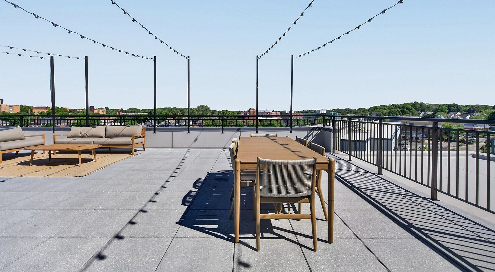 Un espacio al aire libre con una mesa, sillas, un sofá y una barandilla.