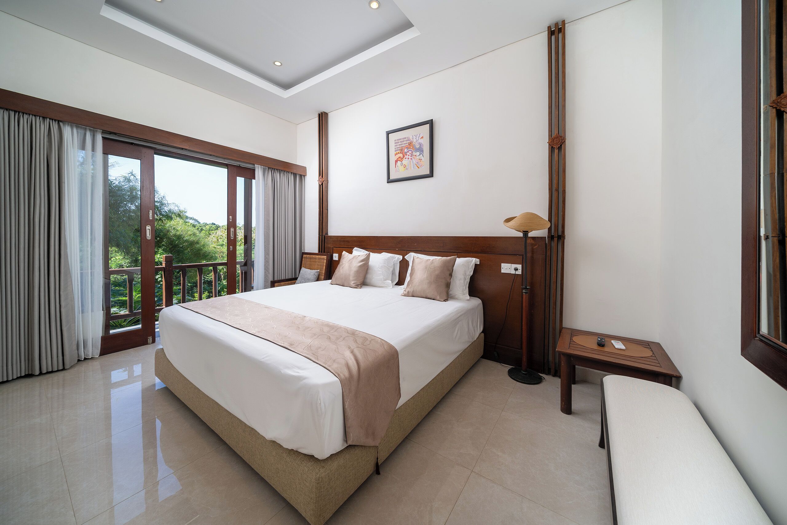 Un dormitorio espacioso con una cama grande, una mesita de noche y vistas al exterior por una puerta corrediza.