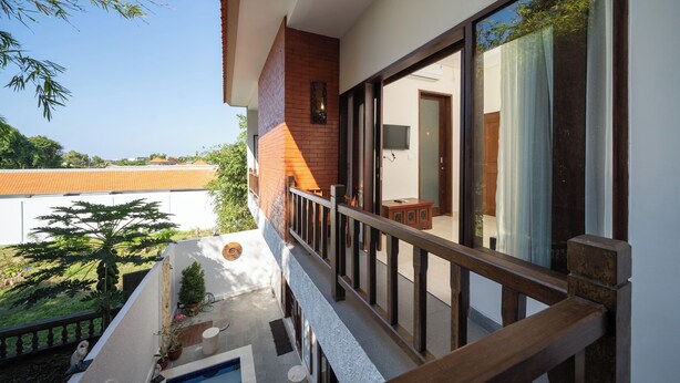 Un balcón con vistas a una piscina, barandilla de madera y una puerta que da a un espacio interior.