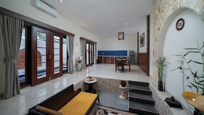 Un amplio salón con un sofá, una mesa de comedor y una escalera que sube a un nivel superior.