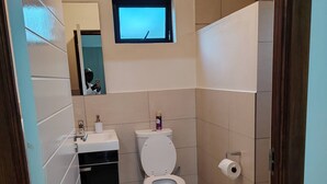 A bathroom with a toilet, sink, mirror, and a small window. - Room-luxurious 2-bedroom Apartment in Ja (Johannesburg)