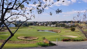 A golf course with a pond, sand bunkers, and a view of a residential area in the background. - Room-luxurious 2-bedroom Apartment in Ja (Johannesburg)