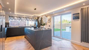 A modern kitchen with a large island, built-in appliances, and a sliding glass door leading to a patio.