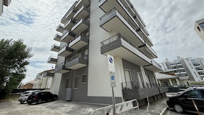 A multi-story residential building with balconies, a parking area, and a sign indicating a no parking zone. - SE293 - Senigallia, two-room apartment just steps from the sea and the center of Senigallia. (Senigallia)
