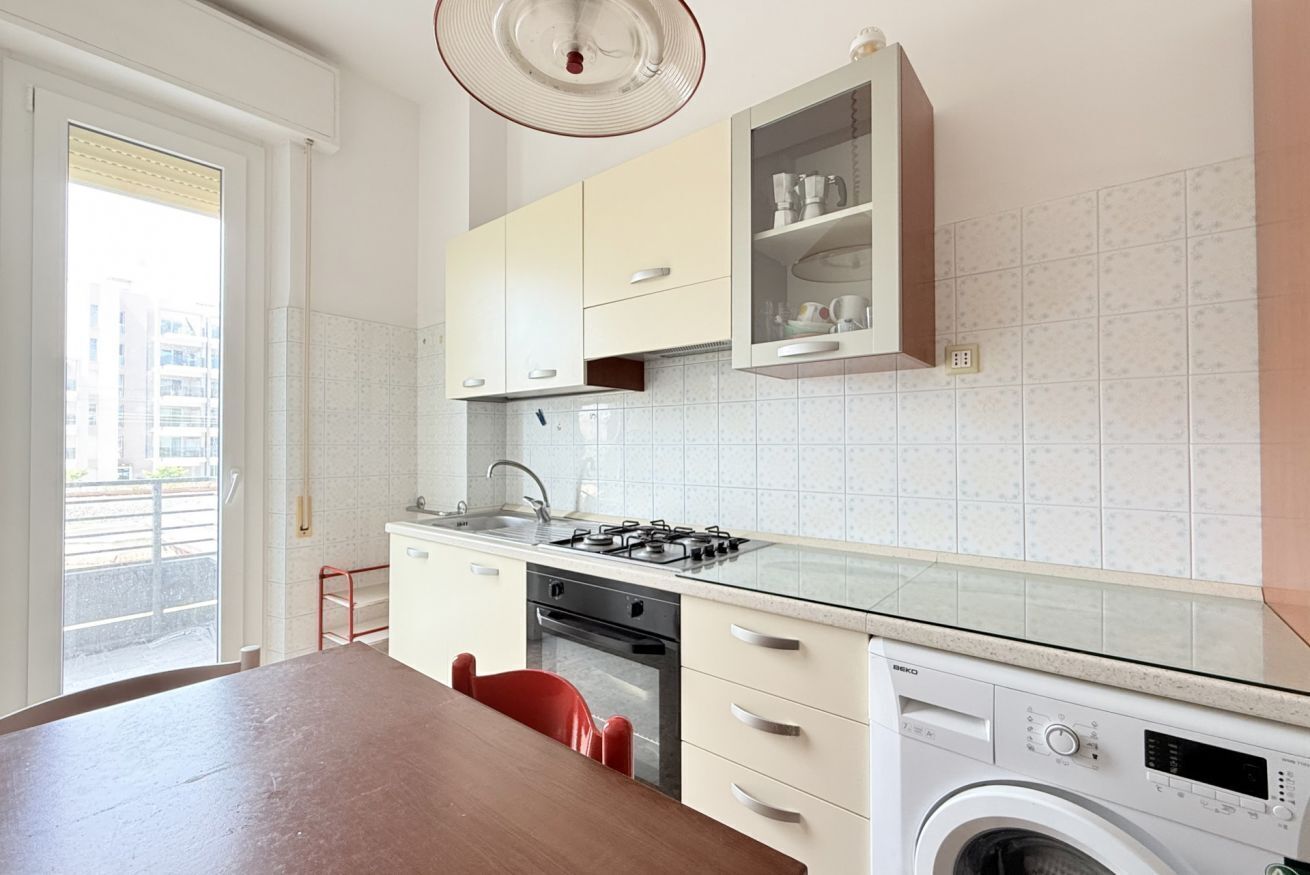 A modern kitchen with a gas stove, built-in oven, and a washing machine.