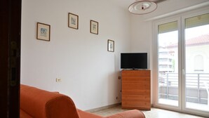 A room with a sofa, a wooden dresser, and a television. There are four framed pictures on the wall. - SE293 - Senigallia, two-room apartment just steps from the sea and the center of Senigallia. (Senigallia)