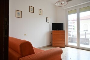 A room with a sofa, a wooden dresser, and a television. There are four framed pictures on the wall. - SE293 - Senigallia, two-room apartment just steps from the sea and the center of Senigallia. (Senigallia)