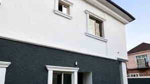 Un edificio a due piani con un piano superiore bianco e un piano inferiore scuro, caratterizzato da una piccola finestra e un ingresso.